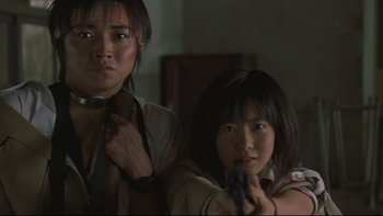 Movie still from “Battle Royale” (2000), directed by Kinji Fukasaku – Two asian women holding guns in a room; Close Up shot, Low angle