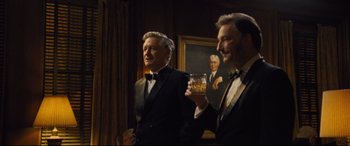 Movie still from “Battle of the Sexes” (2017), directed by Valerie Faris – Two men in tuxedos are holding a glass of whiskey; Medium shot, Over the shoulder angle