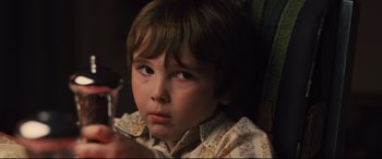 Movie still from “Battle of the Sexes” (2017), directed by Valerie Faris – A young boy is sitting in a chair and holding a cell phone in his hand; Close Up shot, High angle