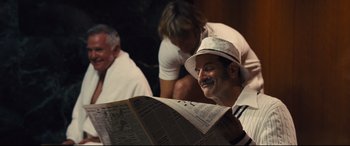 Movie still from “Battle of the Sexes” (2017), directed by Valerie Faris – An older man reading a newspaper while sitting next to another older man; Medium shot, Over the shoulder angle