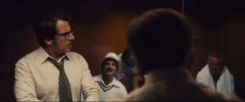 Movie still from “Battle of the Sexes” (2017), directed by Valerie Faris – A group of men standing next to each other in a room; Medium shot, Over the shoulder angle