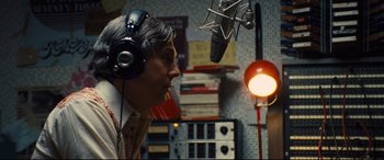 Movie still from “Battle of the Sexes” (2017), directed by Valerie Faris – A man with headphones is listening to a microphone; Close Up shot, Low angle