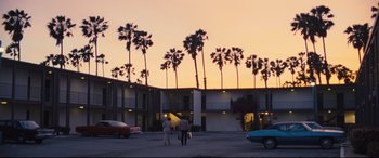 Movie still from “Battle of the Sexes” (2017), directed by Valerie Faris – Two people are standing in a parking lot near palm trees at sunset; Extreme Wide shot, Low angle