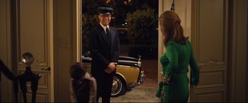 Movie still from “Battle of the Sexes” (2017), directed by Valerie Faris – A man in a suit and hat standing in front of a yellow car; Medium shot, Over the shoulder angle