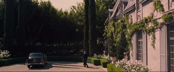 Movie still from “Battle of the Sexes” (2017), directed by Valerie Faris – A man walking down a path in front of a house; Wide shot, High angle