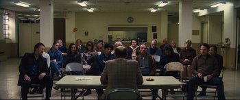 Movie still from “Battle of the Sexes” (2017), directed by Valerie Faris – A group of people sitting around a table with a man sitting at the head of the table; Wide shot, High angle