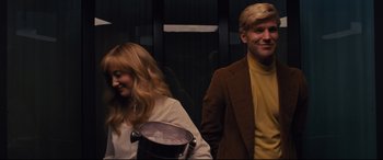 Movie still from “Battle of the Sexes” (2017), directed by Valerie Faris – A man and a woman standing next to each other in front of an elevator; Medium shot, Low angle