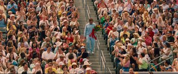 Movie still from “Battle of the Sexes” (2017), directed by Valerie Faris – A crowd of people sitting in a stadium with a man walking up the stairs; Extreme Wide shot, High angle