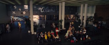 Movie still from “Battle of the Sexes” (2017), directed by Valerie Faris – A group of people sitting in an airport terminal; Extreme Wide shot, High angle