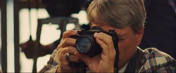 Movie still from “Battle of the Sexes” (2017), directed by Valerie Faris – An older man taking a picture with a camera; Close Up shot, Low angle