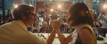 Movie still from “Battle of the Sexes” (2017), directed by Valerie Faris – A man and woman arm wrestling in front of an audience; Medium shot, Over the shoulder angle