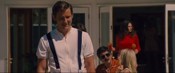 Movie still from “Battle of the Sexes” (2017), directed by Valerie Faris – A man in a white and blue shirt is smiling; Medium shot, Over the shoulder angle