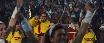 Movie still from “Battle of the Sexes” (2017), directed by Valerie Faris – A man in a yellow and red jacket is in a crowd of people; Medium shot, Over the shoulder angle