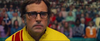 Movie still from “Battle of the Sexes” (2017), directed by Valerie Faris – A person wearing glasses and a yellow shirt; Close Up shot, Low angle