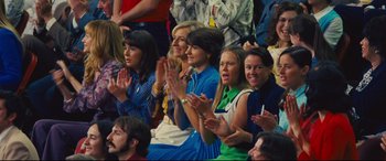 Movie still from “Battle of the Sexes” (2017), directed by Valerie Faris – A group of people sitting in a crowd clapping; Medium shot, Over the shoulder angle