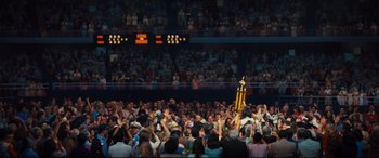 Movie still from “Battle of the Sexes” (2017), directed by Valerie Faris – A crowd of people in a stadium with a trophy in the middle of the crowd; Extreme Wide shot, High angle
