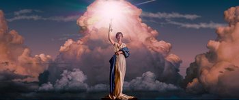 A statue of a woman holding a sword in front of a cloud filled sky