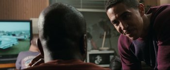 Movie still from “Battle Los Angeles” (2011), directed by Jonathan Liebesman – Two men are talking in a room with a television in the background; Close Up shot, Over the shoulder angle