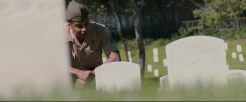 Movie still from “Battle Los Angeles” (2011), directed by Jonathan Liebesman – A man in a military uniform standing next to a headstone; Medium shot, Low angle
