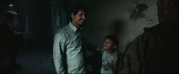 Movie still from “Battle Los Angeles” (2011), directed by Jonathan Liebesman – A man and a boy standing next to each other in a dark room; Medium shot, Over the shoulder angle