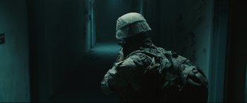 Movie still from “Battle Los Angeles” (2011), directed by Jonathan Liebesman – A man in a helmet is standing in a dark room; Medium shot, Low angle