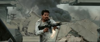 Movie still from “Battle Los Angeles” (2011), directed by Jonathan Liebesman – A man holding a gun while standing in front of smoke; Medium shot, Over the shoulder angle