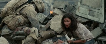 Movie still from “Battle Los Angeles” (2011), directed by Jonathan Liebesman – A woman is laying on the ground next to a man; Medium shot, Over the shoulder angle