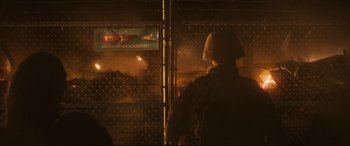 Movie still from “Battle Los Angeles” (2011), directed by Jonathan Liebesman – A man standing in front of an airport fence; Wide shot, Over the shoulder angle