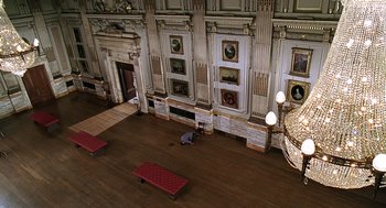 Movie still from “Bean” (1997), directed by Mel Smith – A man kneeling on the floor in front of a wall; Extreme Wide shot, High angle