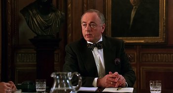 Movie still from “Bean” (1997), directed by Mel Smith – A man in a suit and bow tie sitting at a table; Close Up shot, Low angle