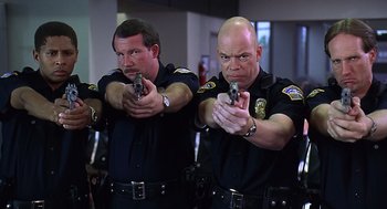 Movie still from “Bean” (1997), directed by Mel Smith – A couple of men in police uniforms holding guns; Medium shot, Low angle