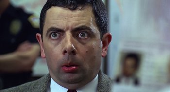 Movie still from “Bean” (1997), directed by Mel Smith – A person wearing a suit and tie; Close Up shot, Low angle