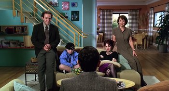 Movie still from “Bean” (1997), directed by Mel Smith – A group of people sitting on a couch in a living room; Wide shot, High angle