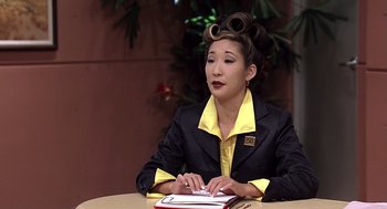 Movie still from “Bean” (1997), directed by Mel Smith – A woman sitting at a table with a book in front of her; Close Up shot, High angle