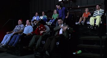 Movie still from “Bean” (1997), directed by Mel Smith – A group of people sitting in a theater watching a movie; Wide shot, High angle