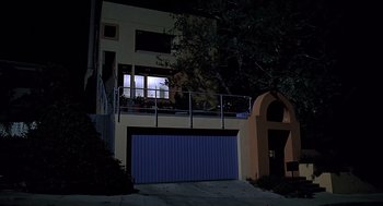 Movie still from “Bean” (1997), directed by Mel Smith – A house with a blue garage door at night time; Extreme Wide shot, Low angle