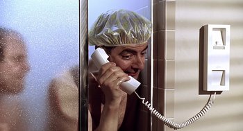 Movie still from “Bean” (1997), directed by Mel Smith – A man in a shower talking on a phone; Close Up shot, Low angle