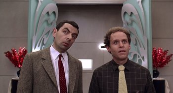 Movie still from “Bean” (1997), directed by Mel Smith – A couple of men standing next to each other; Medium shot, Low angle