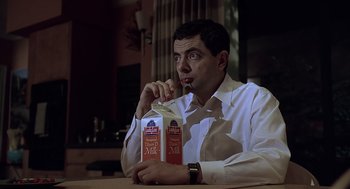 Movie still from “Bean” (1997), directed by Mel Smith – A man sitting at a table with a bottle of milk; Close Up shot, Low angle