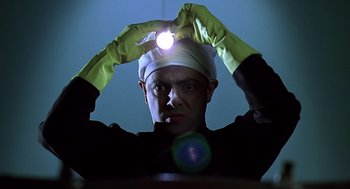 Movie still from “Bean” (1997), directed by Mel Smith – A man with a head lamp on his head; Close Up shot, Low angle