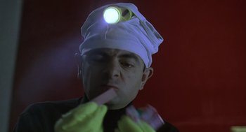 Movie still from “Bean” (1997), directed by Mel Smith – A man with a head lamp on his head; Close Up shot, Low angle
