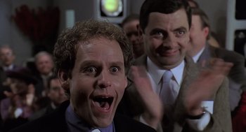 Movie still from “Bean” (1997), directed by Mel Smith – Two men in suits and ties smiling for the camera; Close Up shot, Low angle