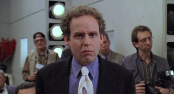 Movie still from “Bean” (1997), directed by Mel Smith – A man in a black suit and a white neck tie; Close Up shot, Over the shoulder angle