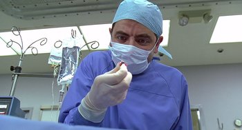 Movie still from “Bean” (1997), directed by Mel Smith – A man wearing a surgical mask holding a tooth brush in his mouth; Close Up shot, Low angle