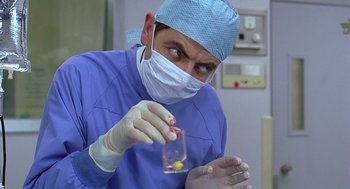 Movie still from “Bean” (1997), directed by Mel Smith – A doctor holding a vial of pills in his hand; Close Up shot, Low angle