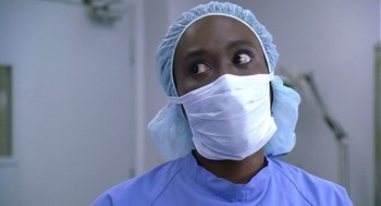 Movie still from “Bean” (1997), directed by Mel Smith – A person wearing a surgical mask and a surgical cap; Close Up shot, Low angle