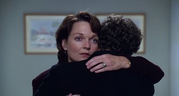 Movie still from “Bean” (1997), directed by Mel Smith – A woman hugging another woman in a room; Close Up shot, Over the shoulder angle