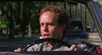 Movie still from “Bean” (1997), directed by Mel Smith – A man driving a car in the middle of the road; Close Up shot, Low angle