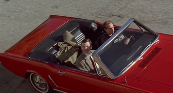 Movie still from “Bean” (1997), directed by Mel Smith – Two men in a red convertible driving down the street; Wide shot, Overhead angle