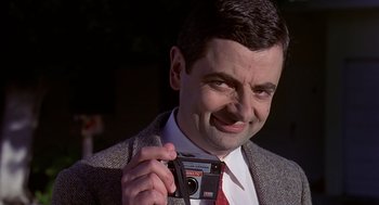 Movie still from “Bean” (1997), directed by Mel Smith – A person holding a camera; Close Up shot, Low angle
